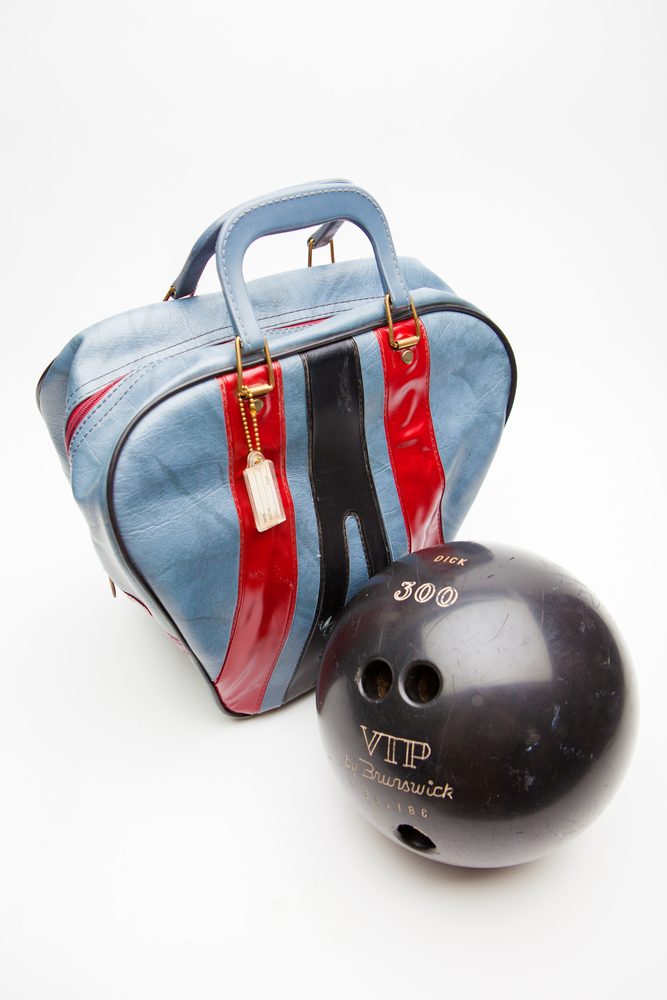 一个天蓝色的保龄球袋，两个红色条纹和一个黑色条纹在前面。保龄球袋有不同的大小和形状。