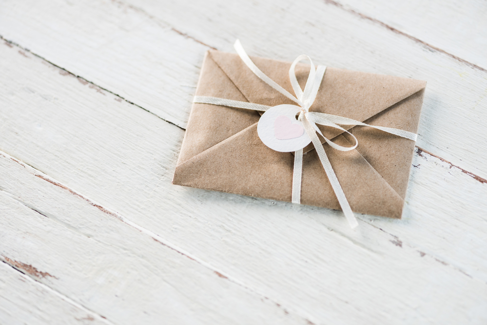 白色木质背景的礼券或礼券，用牛皮纸包装，再配上白色蝴蝶结，都是不错的礼物选择。