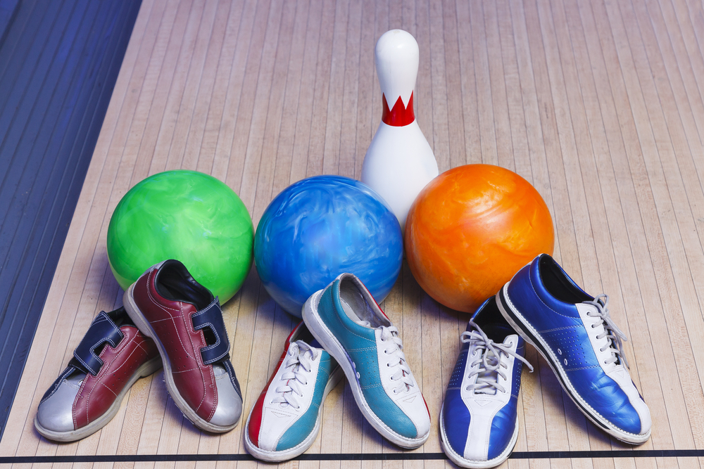 三个绿色，蓝色和橙色的保龄球和三双保龄球鞋，因为一个保龄球鞋被粘干净了。粘保龄球鞋需要对鞋底进行深层清洁。