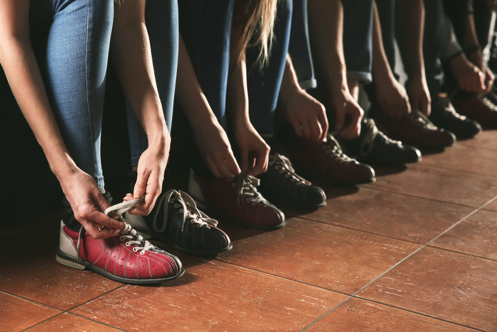 一群人系上租来的保龄球鞋。清洁保龄球鞋最简单的方法是用湿布和消毒剂喷雾。
