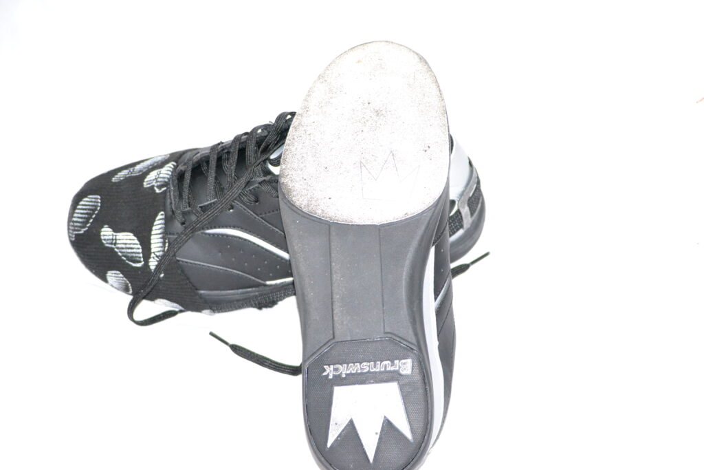 黑色和灰色的布伦瑞克保龄球鞋，在白色的背景上，有一个柔软的布鞋底，因为它是强制性的穿保龄球鞋。
